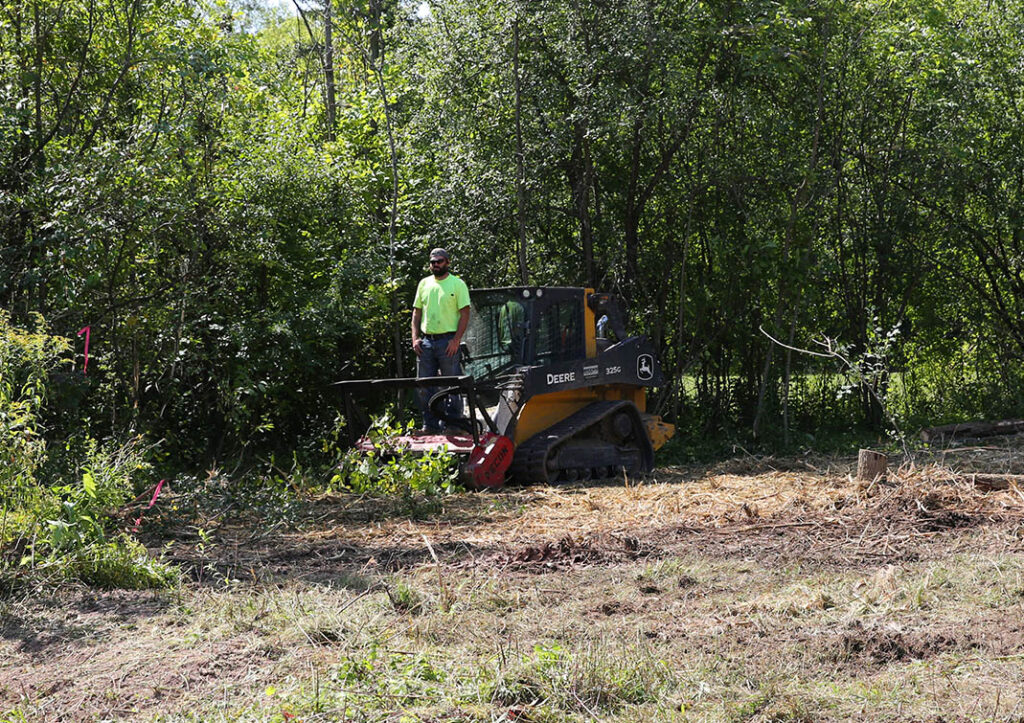 Land Development Company Cody, owner of Wisconsin Land Management, operating a John Deere skid steer during a land clearing project.