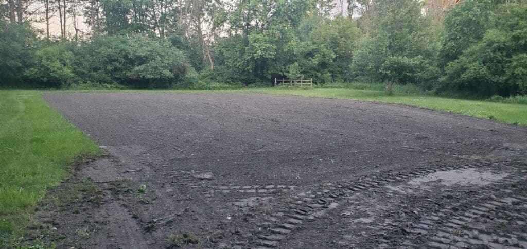 A freshly graded and leveled building pad on a residential property, prepared for a new structure or lawn installation.